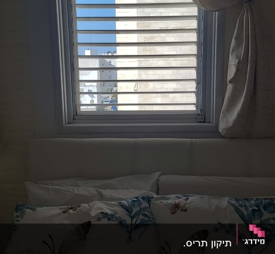 תריסים לבנים פתוחים בחלון עם וילון בצד